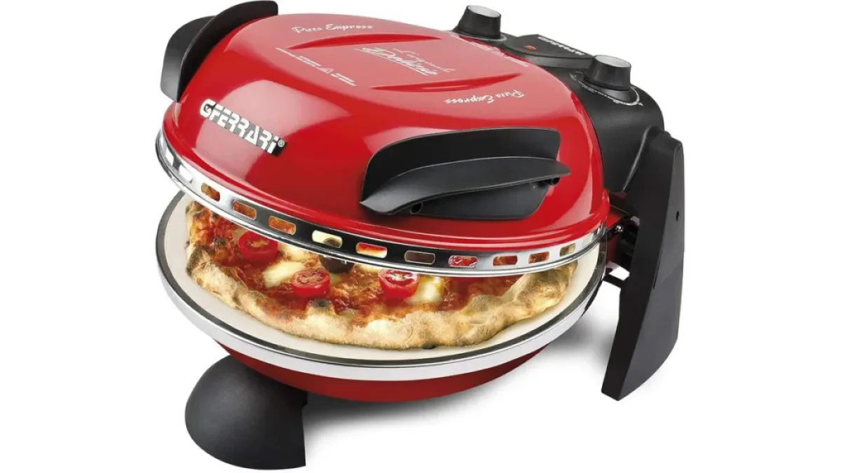 Elektrischer Pizzaofen auf Arbeitstisch mit Pizzastein und aufgelegter Pizza